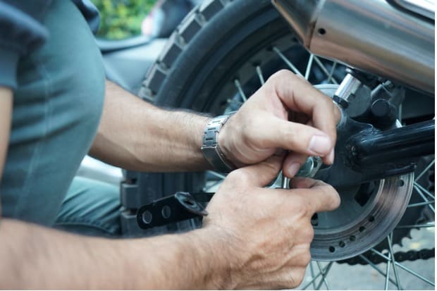 homem realizando a manutenção de sua moto com itens de manutenção