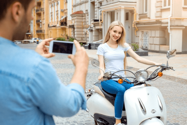 mulher sendo fotografada em cima de um tipo de moto
