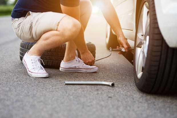 homem trocando seu pneu na estrada